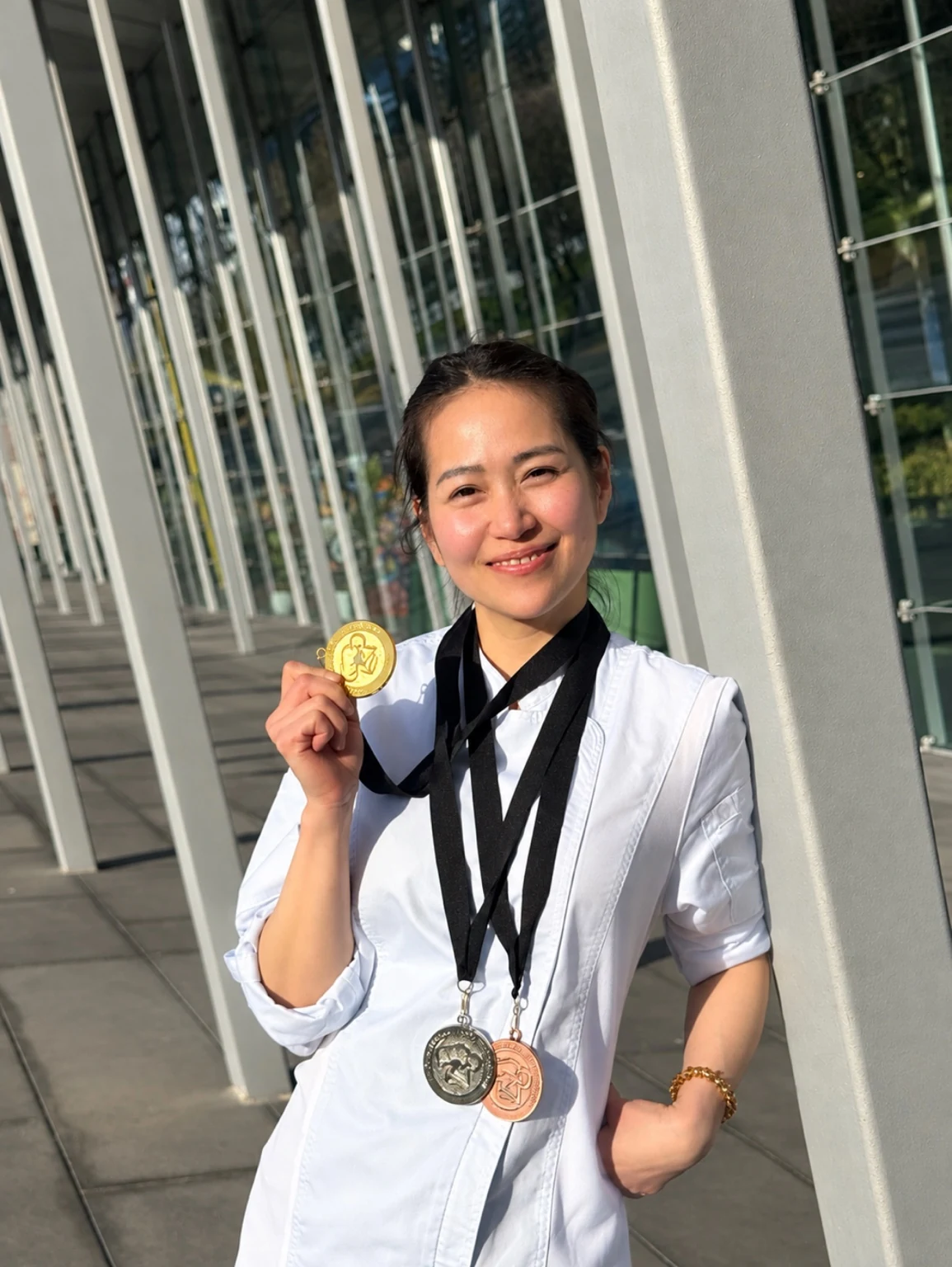 Chef Blue holding a culinary medal and wearing her competition medals outdoors
