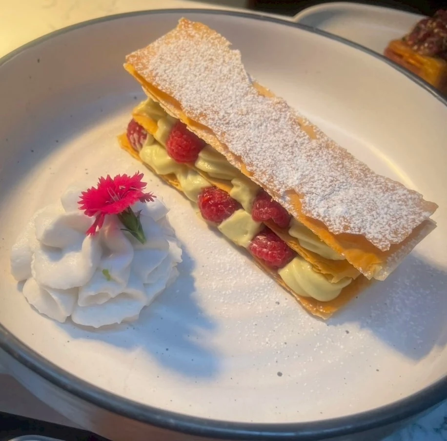 Layered pandan custard millefeuille with fruit and delicate edible flowers